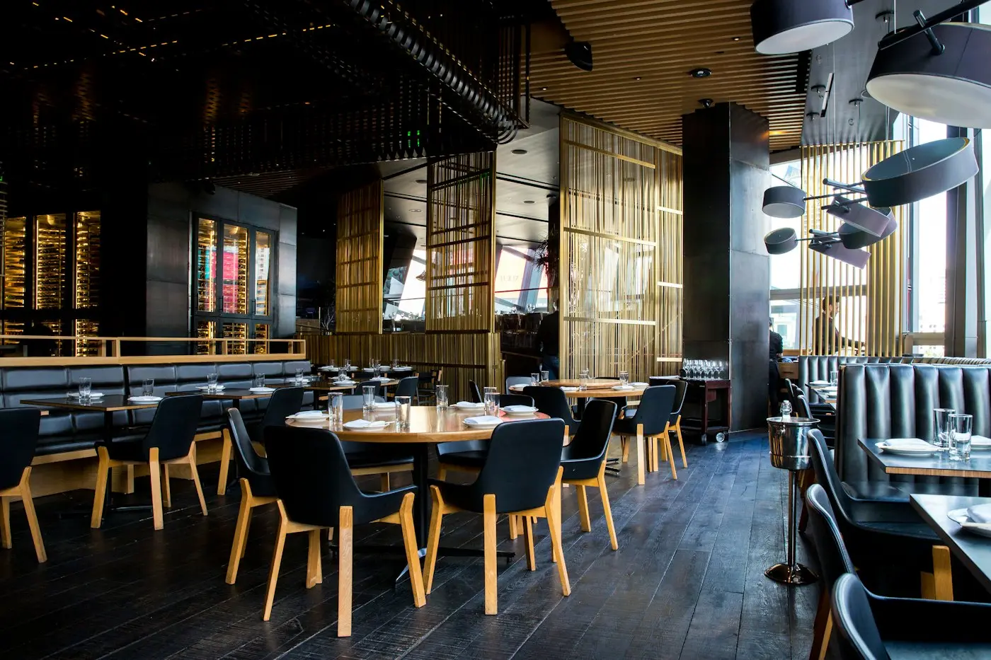 A warm, busy restaurant dining room with copper pendant lamps